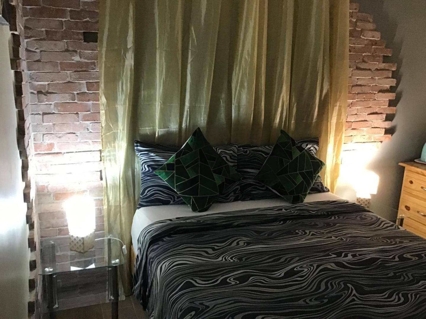 Bedroom with a double bed, exposed brick wall and golden curtains