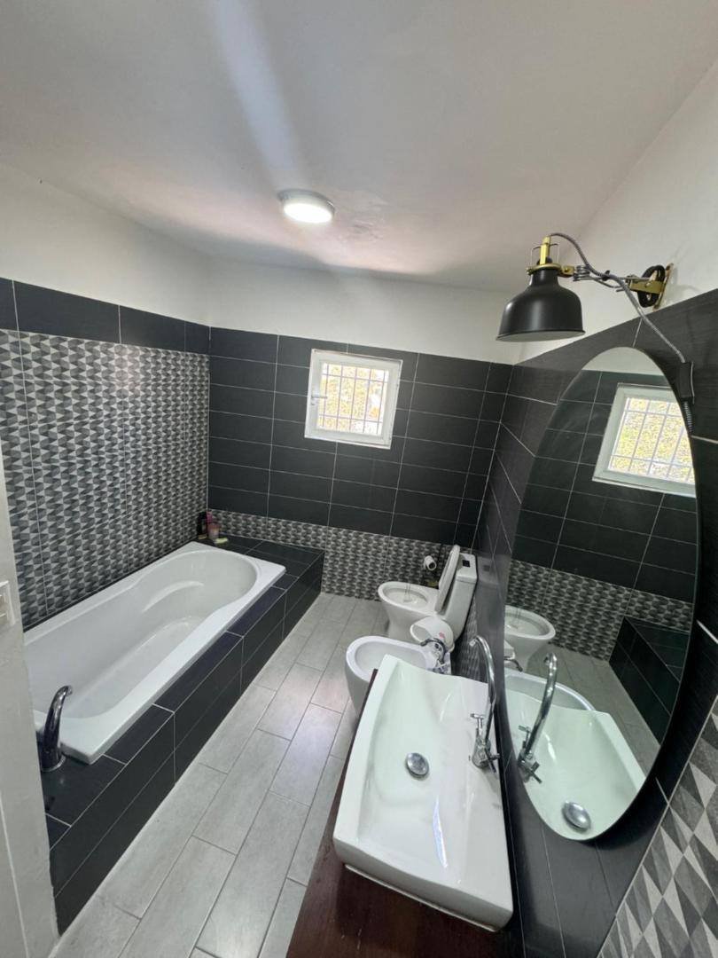 Bathroom with a bathtub, double sink and black tiles